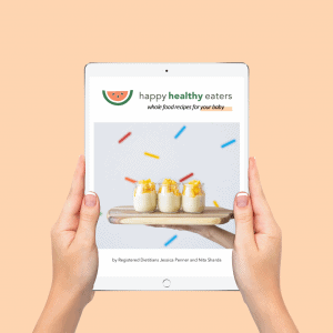 hands holding iPad with cover of whole food recipes for your baby on a peach background