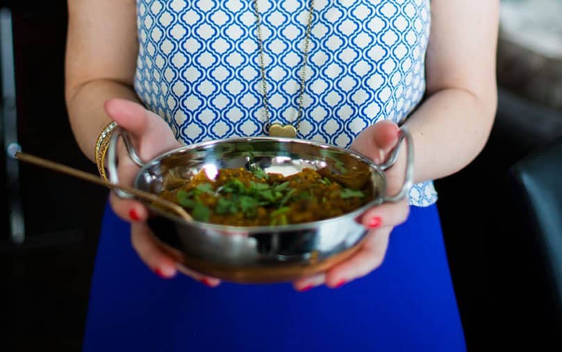 woman holding indian eggplant dish