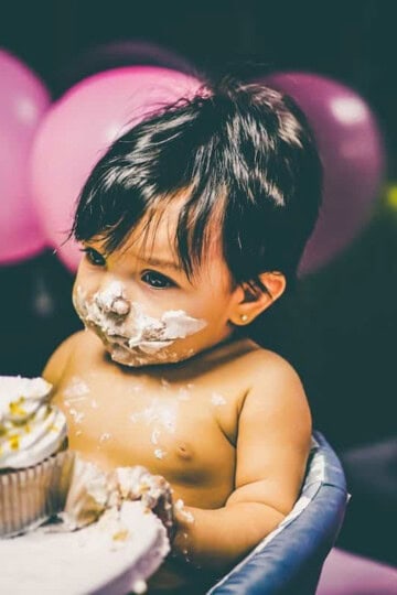 baby at the table with what appears to be cake on their face