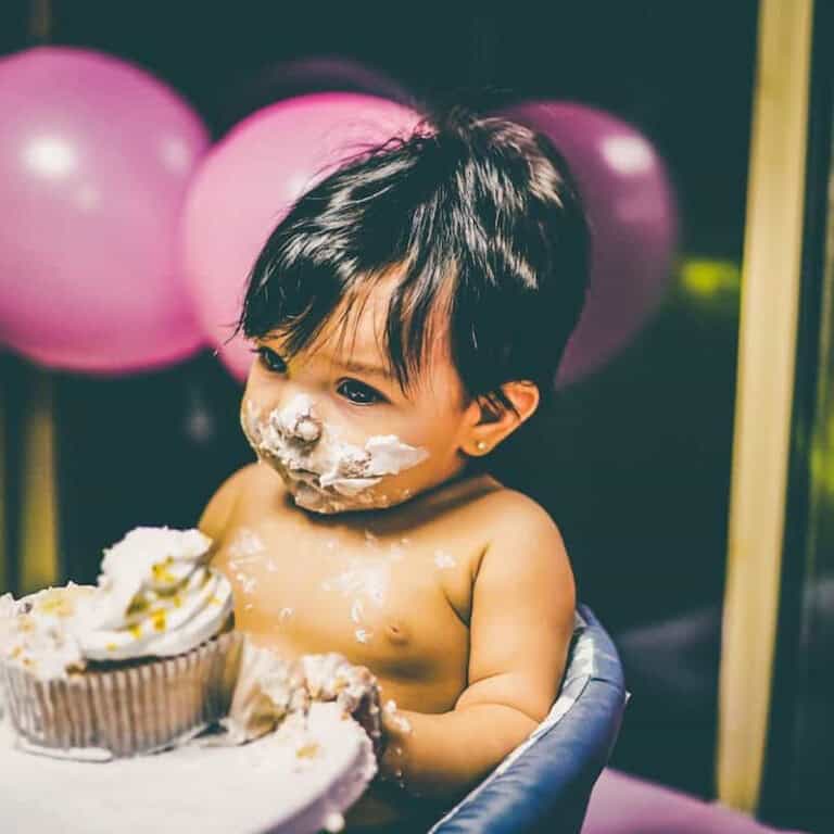 baby at the table with what appears to be cake on their face