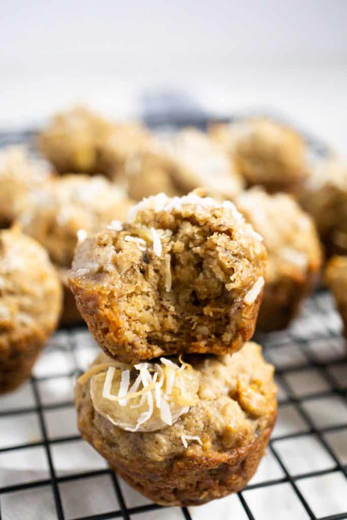 Close up of coconut baby banana muffins stacked one on top of the other.