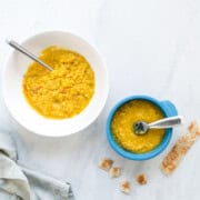 A side by side image of moong dal with the left bowl being suitable for the whole family and the right bowl being just right for baby. Paratha on side for dipping.