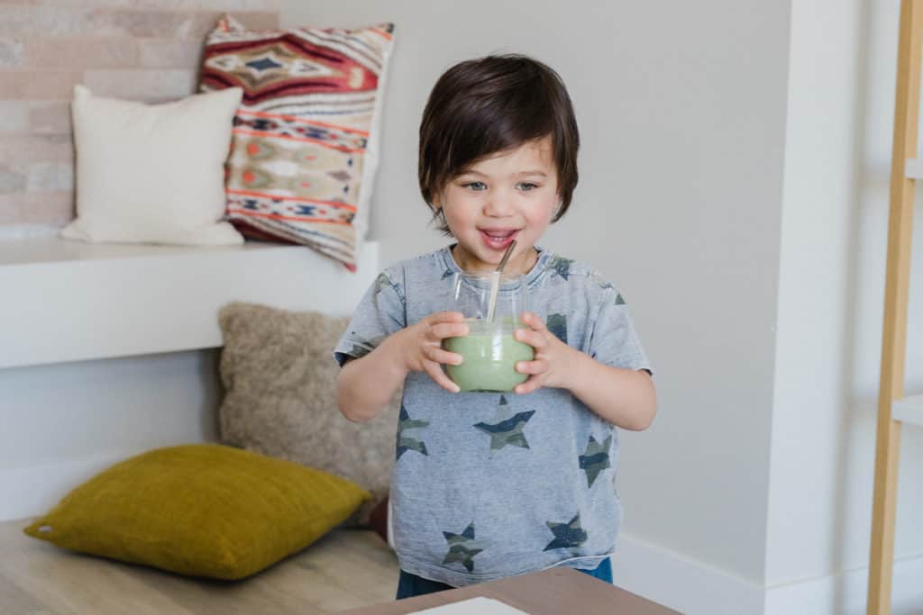 little boy drinking a green smoothie