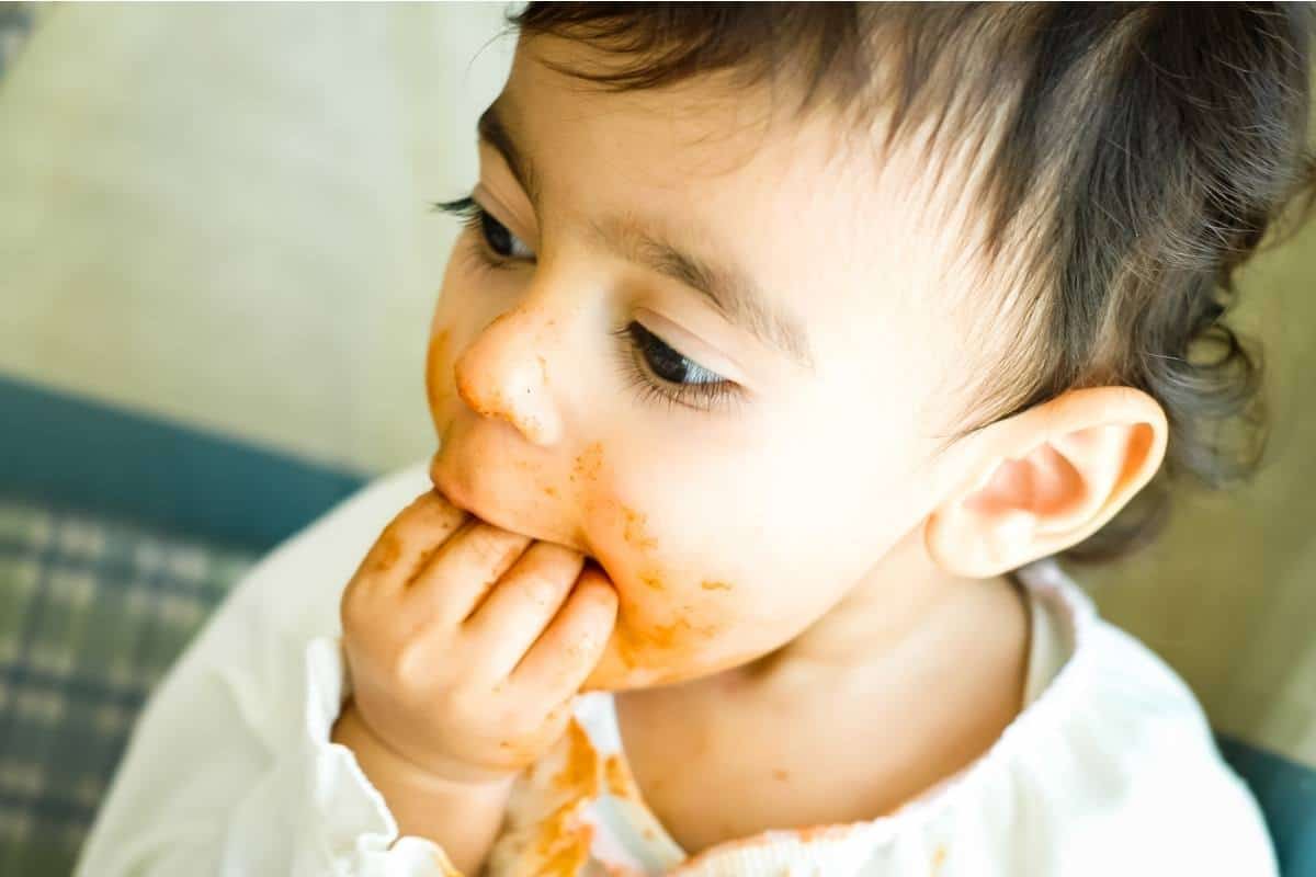 baby stuffing food in mouth