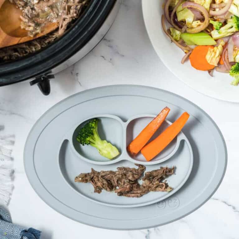 a divided baby plate with shredded beef, steamed carrots and steamed broccoli