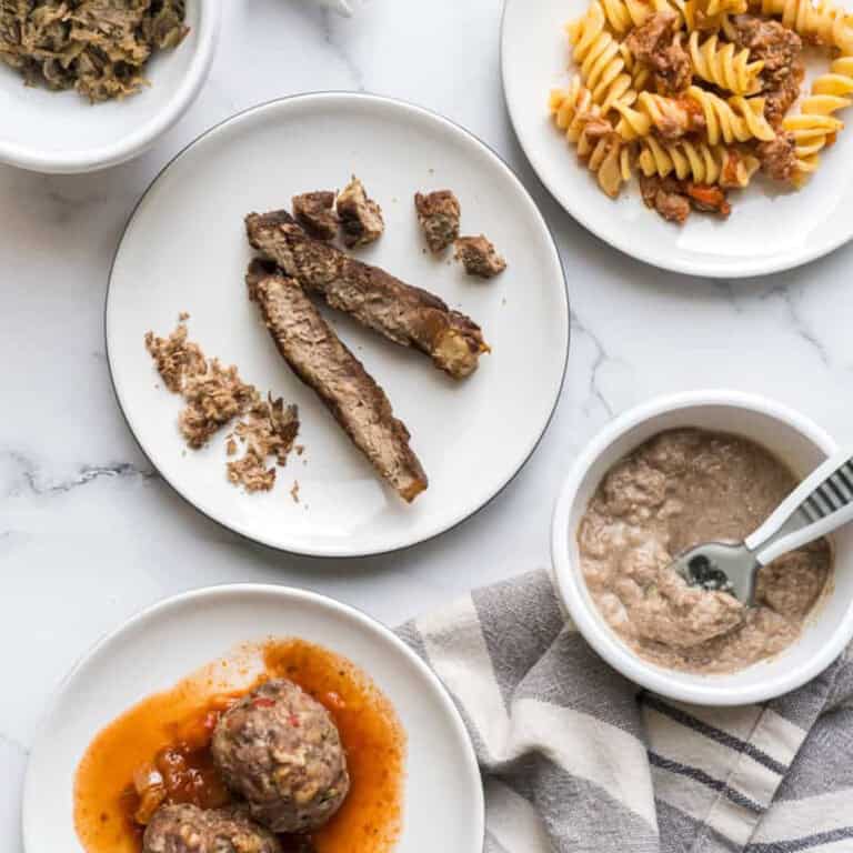 n overhead image of five different beef baby foods: meatballs, steak, pasta sauce, slow cooked beef, and pureed beef