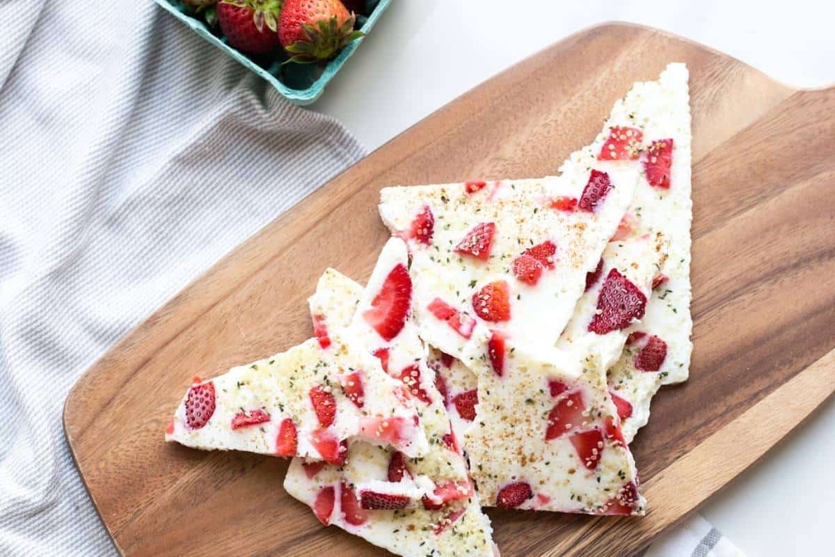 a cutting board with triangles of strawberry frozen yogurt bark with hemp hearts