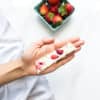 A hand holding a piece of strawberry frozen yogurt bark.