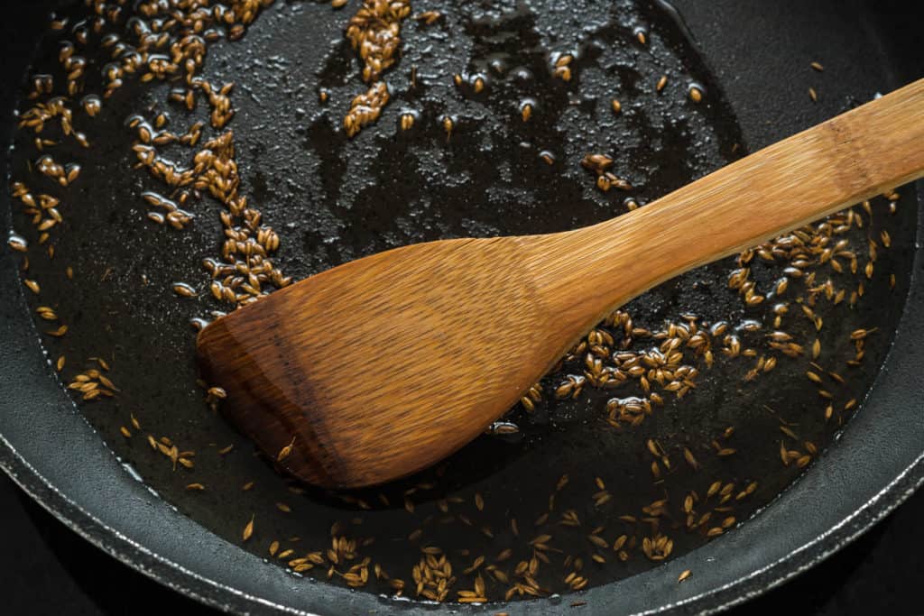 cumin seeds sizzling in oil in a frying pan
