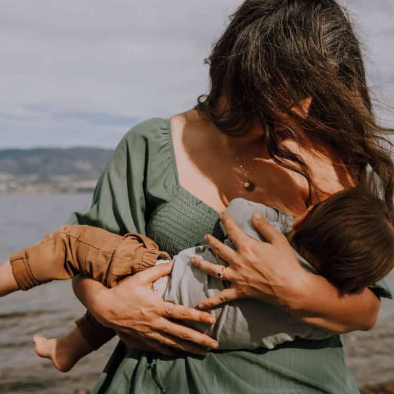 mother breastfeeding baby at beach