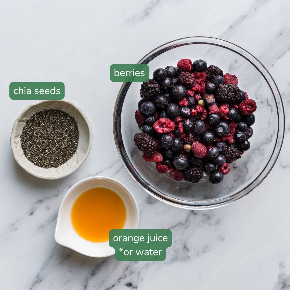 flat lay ingredient shot of berries in a bowl, chia seeds and orange juice