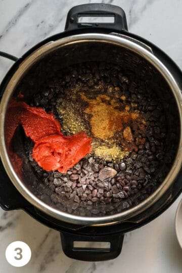 black beans that are cooked in an electric pressure cooker with additional ingredients such as spices and tomato paste
