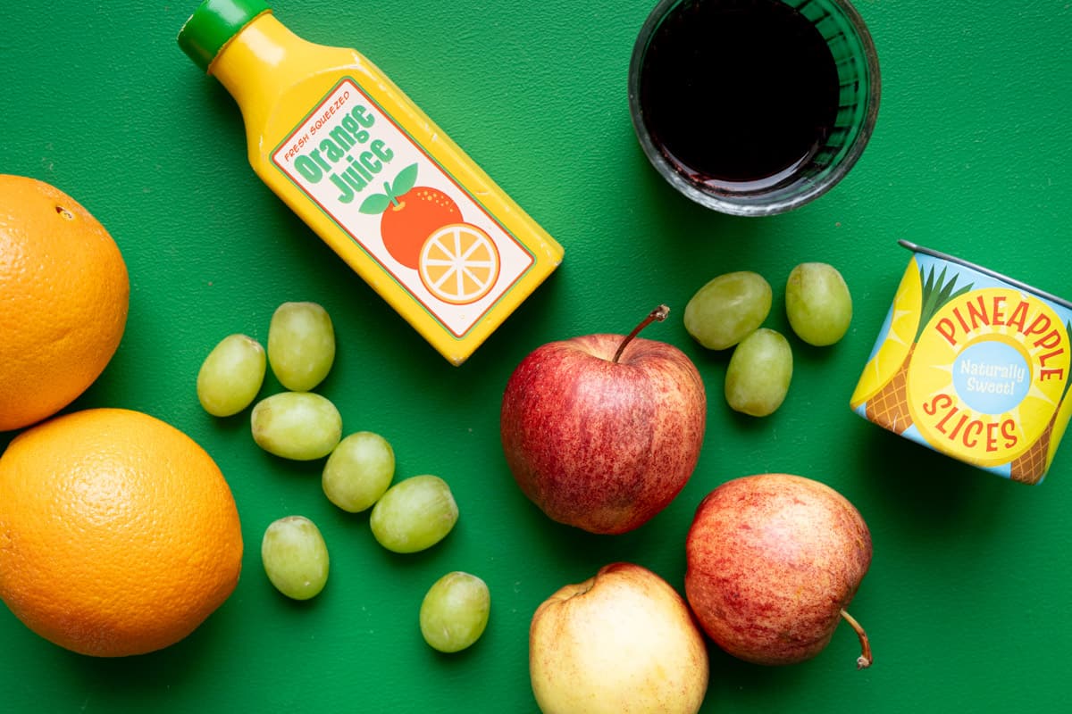 An array of fruit and juices on a green background.