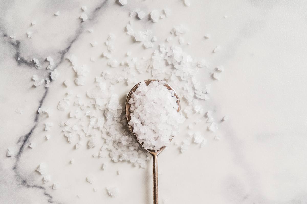 A spoon of course salt on a marble background