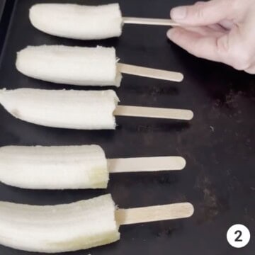 5 bananas on a popsicle stick that have been frozen.