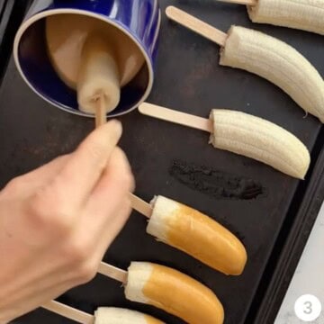 Frozen bananas being dipped in melted peanut butter.