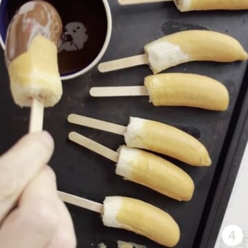 Frozen banana that is being dipped in melted chocolate.