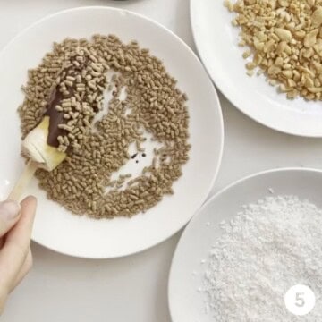 Chocobananos being rolled in a variety of toppings such as bran cereal, chopped peanuts and shredded dried coconut.
