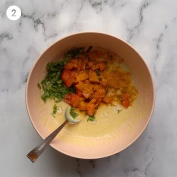 Vegetables such as tomato, carrot and onion along with spices in a bowl of batter - batter is chickpea based. 