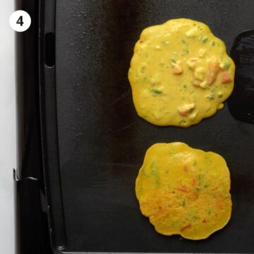 Chilla or chickpea pancakes cooking and about to be flipped on a griddle. 