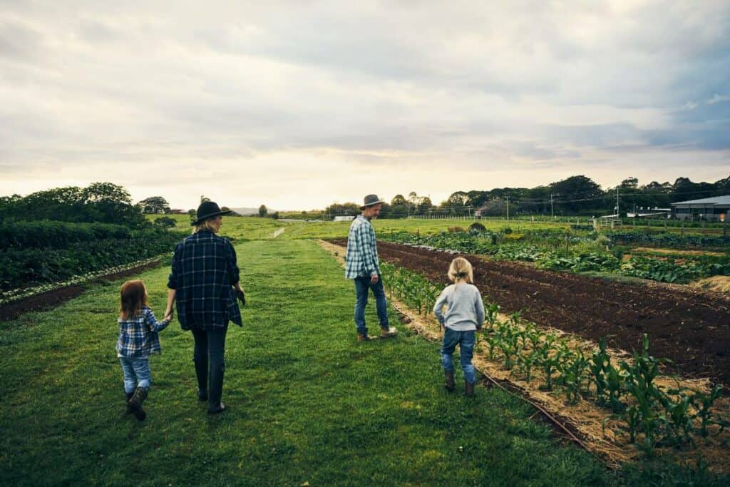 A family with young children walking through their family farm together.