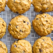 Close up image of freshly baked soft chocolate chip pumpkin cookies on a cooling rack.
