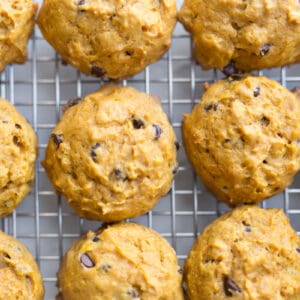 Close up image of freshly baked soft chocolate chip pumpkin cookies on a cooling rack.