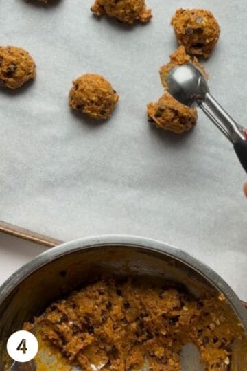 scoops of pumpkin cookie dough being placed with a scoop on a baking sheet
