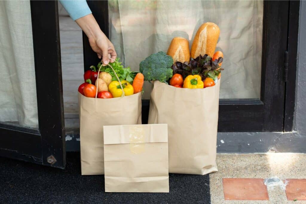 Three bags of groceries left in front of someone's door as part of a grocery delivery haul