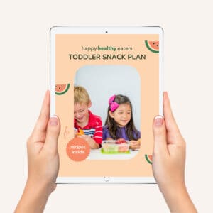 A mockup of two hands holding up an ipad with the cover of Happy Healthy Eaters' Toddler Snack Plan on the screen.
