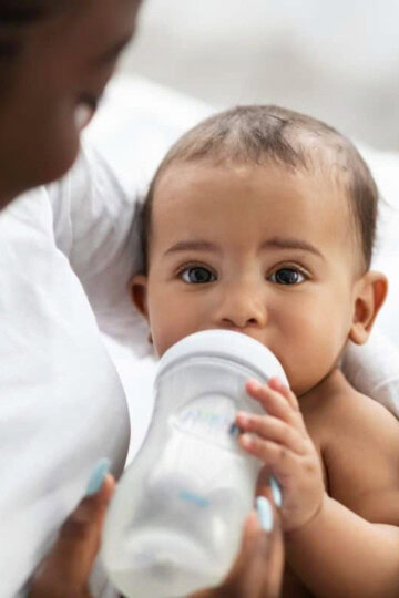 baby held by mother drinking from a bottle
