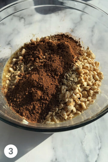 Dry ingredients have been added to the bowl, puffed quinoa, cocoa powder oats. 