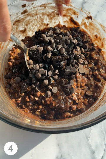 prunes have been added to a bowl along with chocolate chips being folded in. 