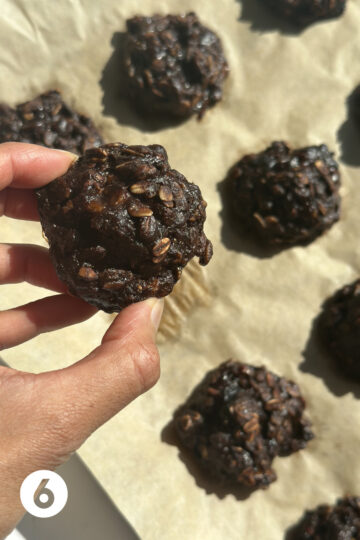 finished baked chocolate prune cookies, with one being held up closer to the screen