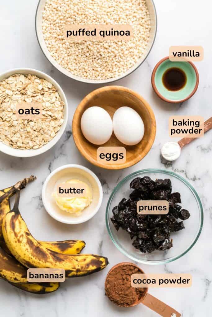 flat lay of ingredients for chocolate prune cookie including puffed quinoa, oats, eggs, banana, vanila, butter and vanilla