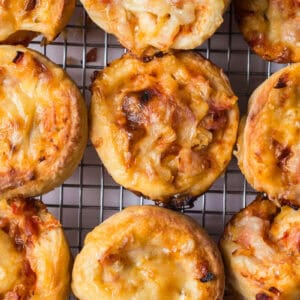 a closeup view of the ham and cheese pizza buns cooling on a baking rack.