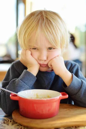 Toddler looking grumpy at table.
