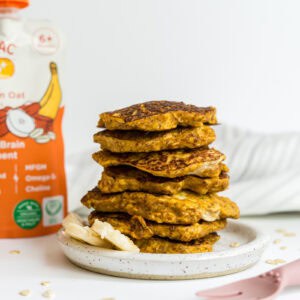 A stack of baby fruit pouch pancakes beside a pouch of Brainiac Neruo+