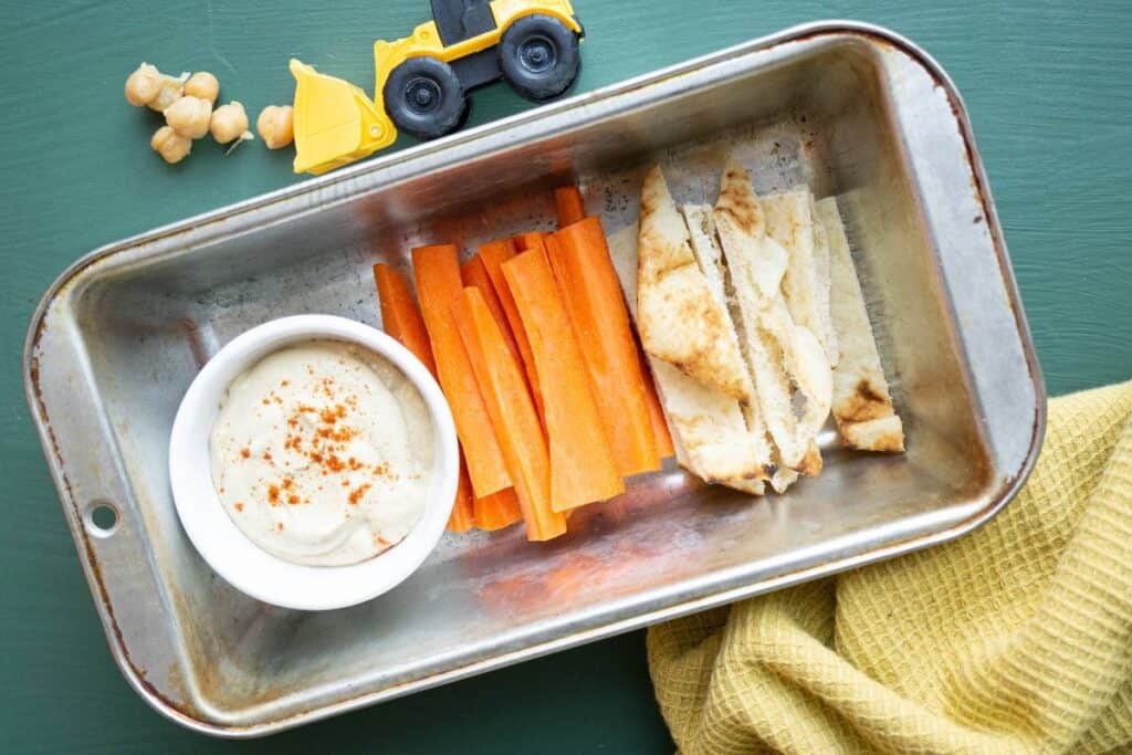 Baby hummus with steamed carrot sticks and pita strips.