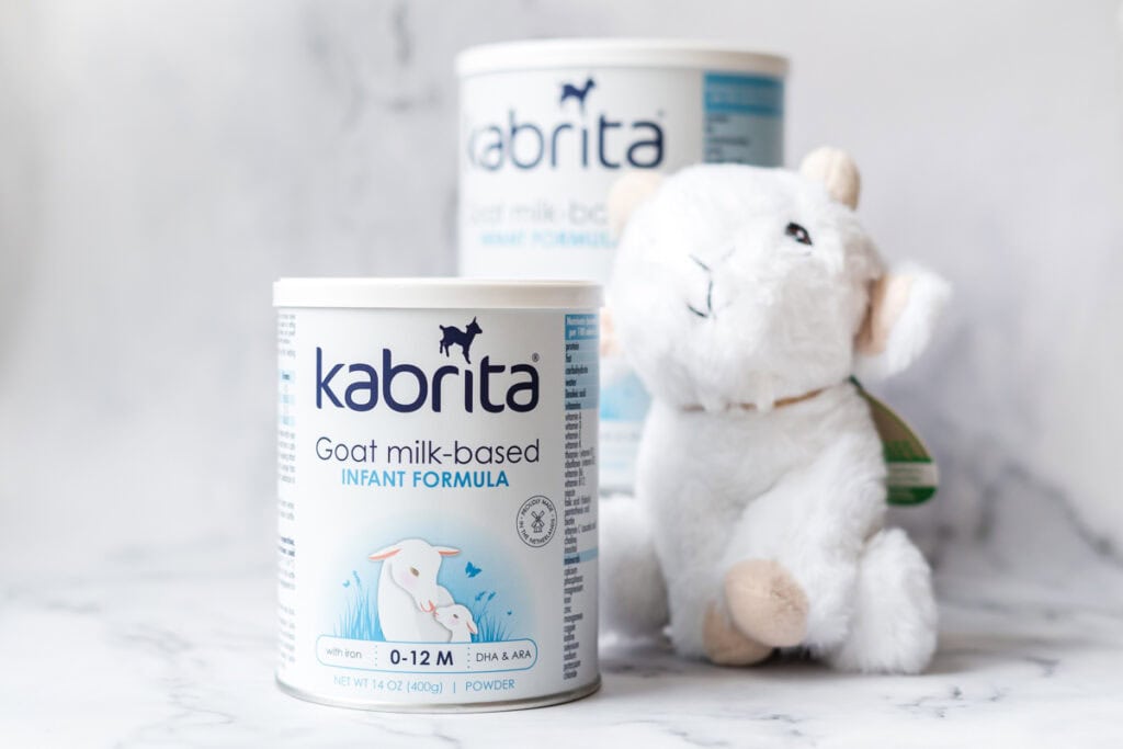 A can of Kabrita goat milk-based infant formula beside a goat stuffy.