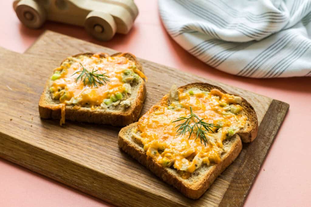 Two ranch tuna melt open faced sandwiches on a serving board.