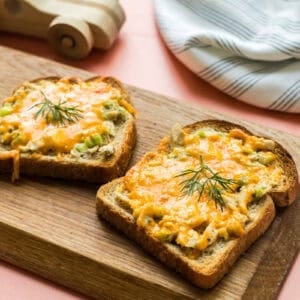 Two ranch tuna melt open faced sandwiches on a serving board.