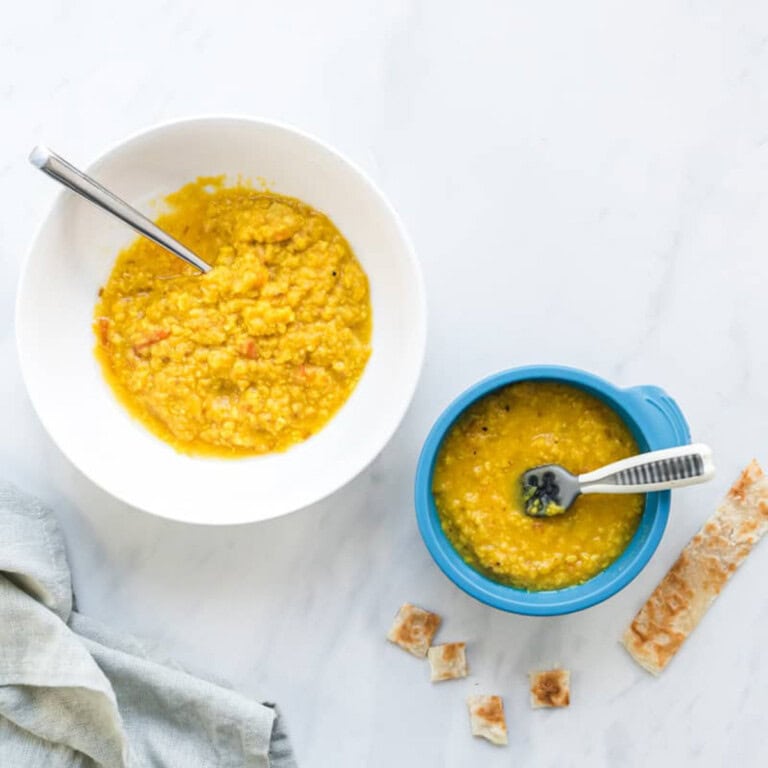 A side by side image of moong dal with the left bowl being suitable for the whole family and the right bowl being just right for baby. Paratha on side for dipping.