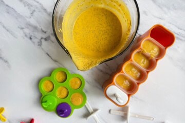 Mango chia pop mixture being poured into popsicle molds.