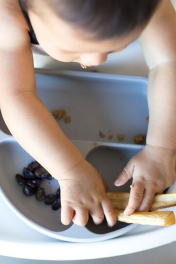 baby throwing food off high chair.