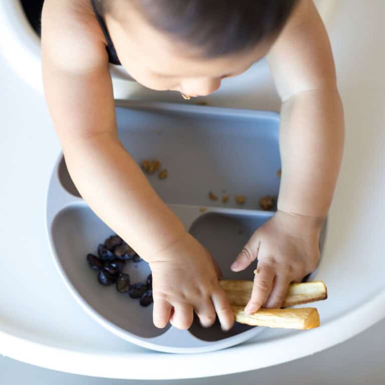 baby throwing food off high chair.