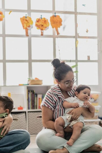 Women sitting on the floor in a mom and me class breastfeeding their toddlers.