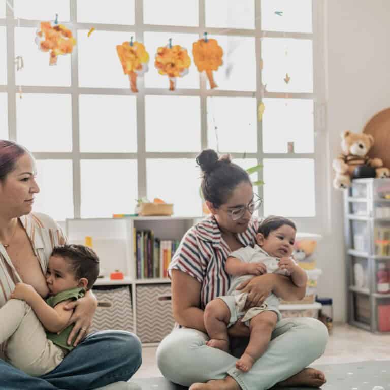 Women sitting on the floor in a mom and me class breastfeeding their toddlers.