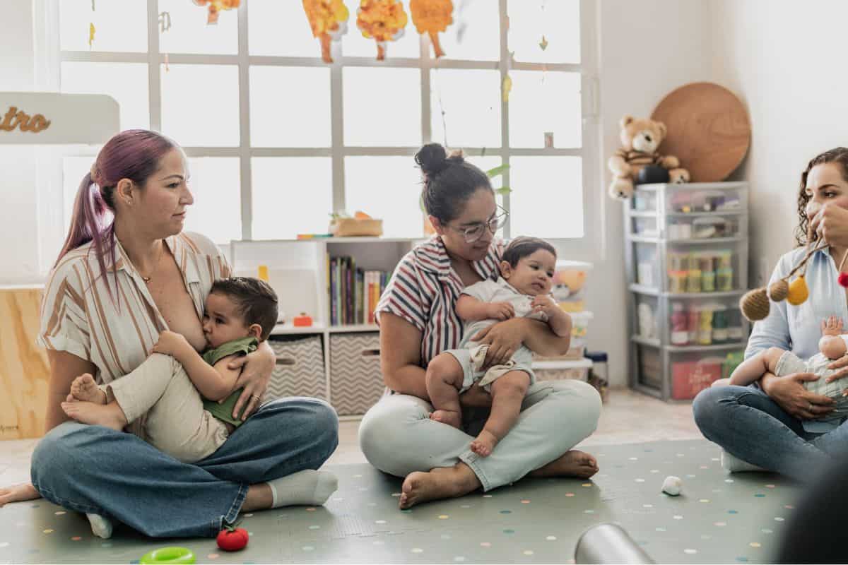 Women sitting on the floor in a mommy and me class breasstfeeding their toddlers.