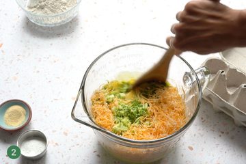Bowl with broccoli and cheese being mixed into the egg mixture.